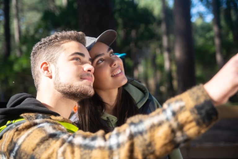 excited-couple-young-hikers-caucasian-man-with-beard-woman-cap-pointing-looking-up-hobby-nature-love-concept (1)